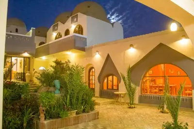 a large white building with a lot of plants at Janat Elsahara Hotel in Luxor