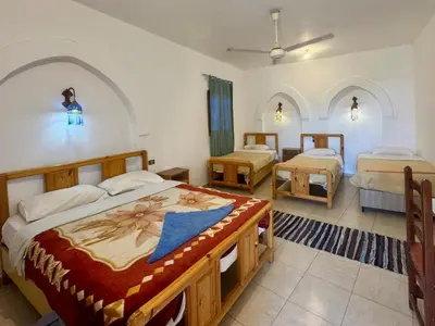 a hotel room with two beds and two tables at Hotel Sheherazade Luxor in Luxor