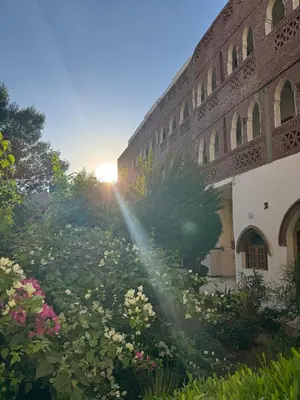 a building with a garden with flowers in front of it at Hotel Sheherazade Luxor in Luxor