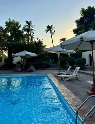 a swimming pool with two chairs and umbrellas at Hotel Sheherazade Luxor in Luxor