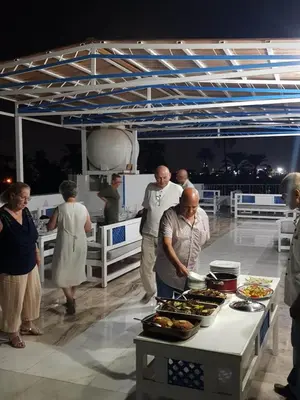 a group of people standing around a table with food at Moon Valley Apartments in Luxor