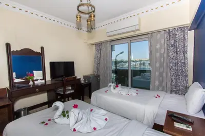 a hotel room with two beds and a desk and a window at Philae Hotel Aswan in Aswan