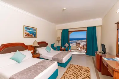 a hotel room with two beds and a balcony at Coral Hills Resort & SPA in Quseir