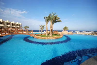 a large swimming pool with a bridge and palm trees at Coral Hills Resort & SPA in Quseir