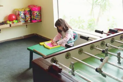 a little girl sitting at a table with a book at Coral Hills Resort & SPA in Quseir