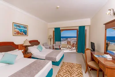 a hotel room with two beds and a desk at Coral Hills Resort & SPA in Quseir