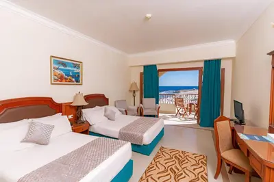 a hotel room with two beds and a desk at Coral Hills Resort & SPA in Quseir