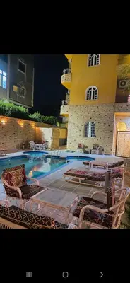 a swimming pool with lounge chairs and a building at Al Gezera Apartments in Luxor