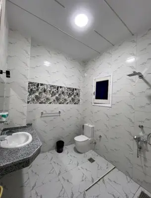 a white bathroom with a sink and a toilet at Al Gezera Apartments in Luxor