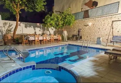 a large swimming pool with a table and chairs at Al Gezera Apartments in Luxor
