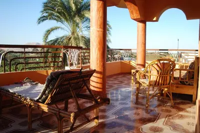 a balcony with chairs and a table and a palm tree at Al Gezera Apartments in Luxor