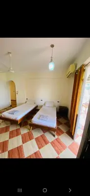 two beds in a room with a checkered floor at Leyla Eco Resort in Luxor