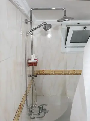 a shower head in a bathroom with white tiles at One Bedroom Chalet managed by Lilly Homes in Hurghada
