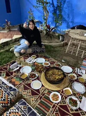 a woman sitting on the ground with a table of food at Golden Palace Garden in Luxor
