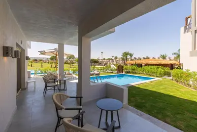 a patio with a pool and tables and chairs at Sunrise Crystal Bay Resort -Grand Select in Hurghada