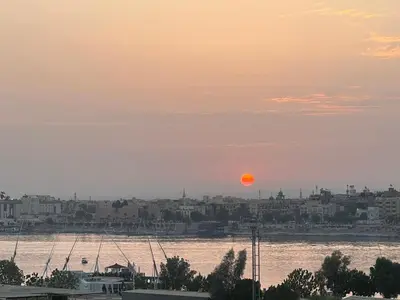 a sunset over the water with a city and a river at Harmony House Luxor in Luxor