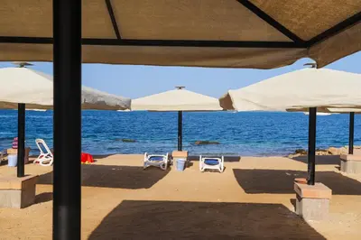 a group of umbrellas and chairs on a beach at Nubian Village Sky, Hurghada in Hurghada