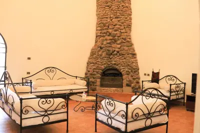 two beds in a room with a stone fireplace at Nubian Holiday House Aswan in Aswan