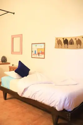 a bedroom with a bed with a blue pillow at Nubian Holiday House Aswan in Aswan