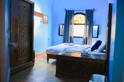 a blue bedroom with a bed and a mirror at Nubian Holiday House Aswan in Aswan