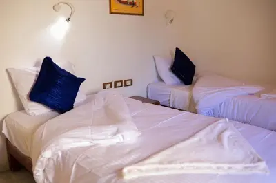 a room with two beds with white sheets and blue pillows at Nubian Holiday House Aswan in Aswan