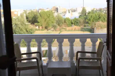 a balcony with two chairs and a view of the city at Memnoun house in Luxor