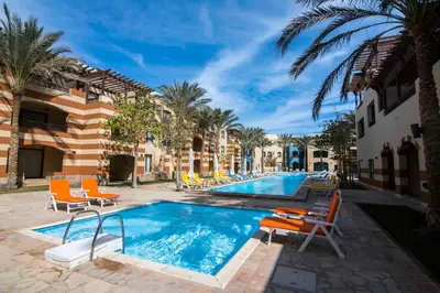 a pool at a resort with chairs and palm trees at Marina Residence Suites Port Ghalib in Port Ghalib