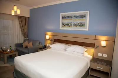 a hotel room with a large bed and a chair at Swiss Inn Resort Hurghada in Hurghada