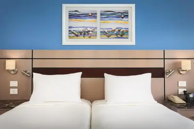 two beds in a hotel room with a painting on the wall at Swiss Inn Resort Hurghada in Hurghada
