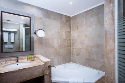 a bathroom with a tub and a sink and a mirror at Swiss Inn Resort Hurghada in Hurghada