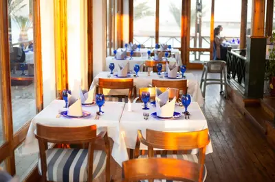 a dining room with tables and chairs with blue glasses at Swiss Inn Resort Hurghada in Hurghada