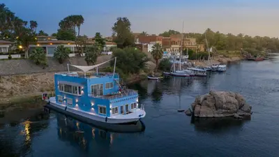 a blue boat is docked in a river at Anakob in Aswan