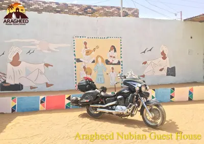 a motorcycle parked in front of a painted wall at Nubian Kingdom Aragheed House in Aswan