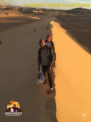 two men are walking on the beach at Nubian Kingdom Aragheed House in Aswan