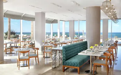 a restaurant with tables and chairs and the ocean at Hilton Hurghada Plaza Hotel in Hurghada