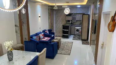 a living room with blue couches and a kitchen at Apartment in Center of Hurghada in Hurghada