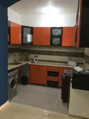 a kitchen with orange cabinets and a washing machine at The Brown House in Luxor