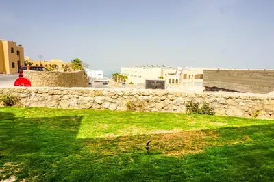 a grassy field with a stone wall and the ocean at Studio at Hurghada- NS2 in Hurghada