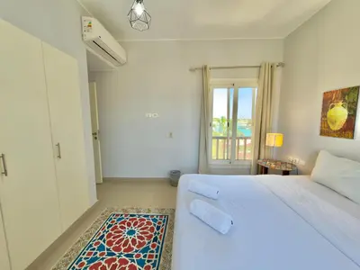 a white bedroom with a bed and a window at Golden Apartments El Gouna in Hurghada