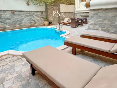 a swimming pool with two chaise lounges next to at Elite Suites Hurghada in Hurghada