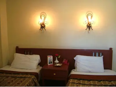two beds in a hotel room with lights on the wall at Orchida St. George Hotel in Aswan