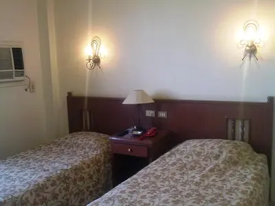 two beds in a hotel room with lights on the wall at Orchida St. George Hotel in Aswan