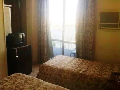 a room with two beds and a television and a window at Orchida St. George Hotel in Aswan
