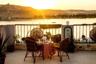a table and chairs on a balcony with a view of a lake at Marhaba Palace Hotel in Aswan