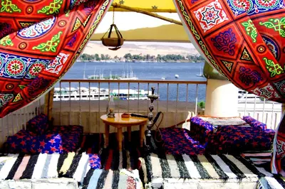 a balcony with chairs and a table and a view of the water at Marhaba Palace Hotel in Aswan