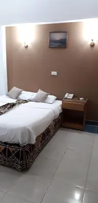 a hotel room with two beds and a night stand at Marhaba Palace Hotel in Aswan