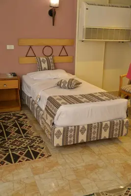 a bedroom with two beds and a table at Marhaba Palace Hotel in Aswan