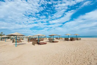 a beach with umbrellas and chairs and the ocean at Shams Safaga Resort in Hurghada