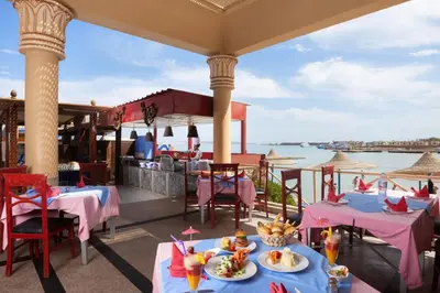 a restaurant with tables and a view of the water at King Tut Aqua Park Beach Resort in Hurghada