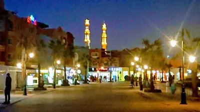 a city street at night with a clock tower in the background at Exoticky apartman in Hurghada